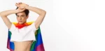 beautiful-gay-man-with-glitter-face-wearing-crop-top-rainbow-lgbt-flag-posing-against-white-b_1258-107589